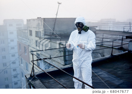 Worker scientist wearing protective coverall and gas mask doing ecological tests on the roof 68047677