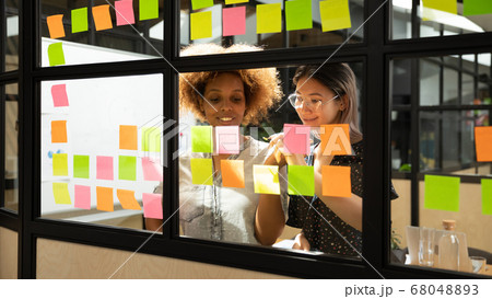 Happy african and asian businesswomen working with sticky notes 68048893