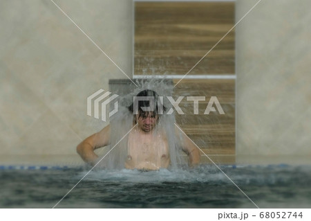 Young man enjoying pool spa day in relaxing vacation resort. Hydro massage for neck pain.Relaxing under water jet,neck and spine massage. 68052744