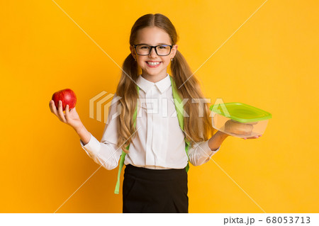 Happy Schoolgirl Holding Lunchbox And Apple Standing In Studio 68053713