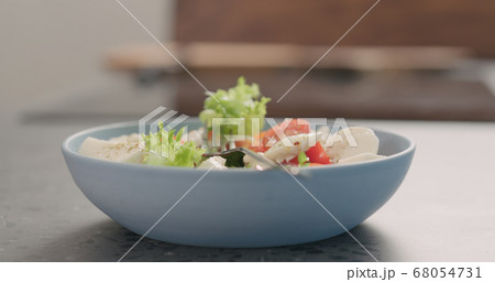 tries salad with frisee lettuce, tomatoes amd mozzarella in a blue bowl on kitchen countertop 68054731