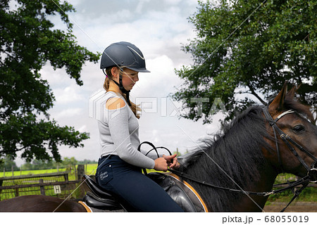 Portrait of cute girl in helmet horseback riding on brown horse копия 68055019