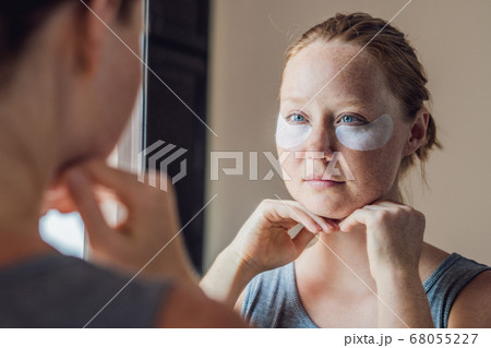 Portrait of Beauty Red-haired woman with eye patches showing an effect of perfect skin. Spa Girl 68055227