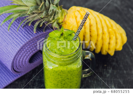 Green smoothies made of spinach and pineapple and a yoga mat. Healthy eating and sports concept Green smoothies made of spinach and pineapple and a yoga mat. Healthy eating and sports concept 68055255