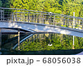 in a city park a metal bridge over a river at dawn. 68056038