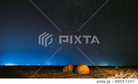 Night Starry Sky Above Haystacks In Summer Agricultural Field. Night Stars Above Rural Landscape With Hay Bales After Harvest. Agricultural Panorama Night Starry Sky Above Haystacks In Summer Agricultural Field. Night Stars Above Rural Landscape With Hay Bales After Harvest. Agricultural Panorama 68057247