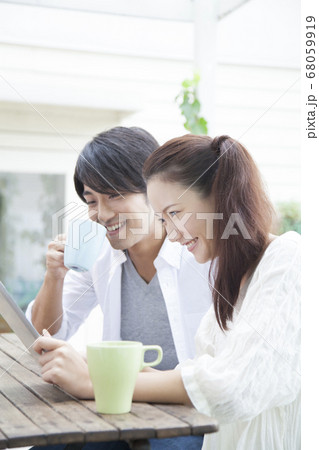 テラスでタブレットPCを見るカップル 68059919