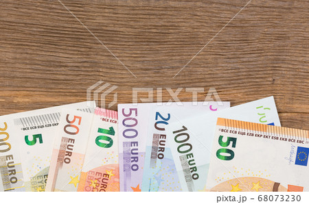 Lots of euro bills on wooden background. 68073230