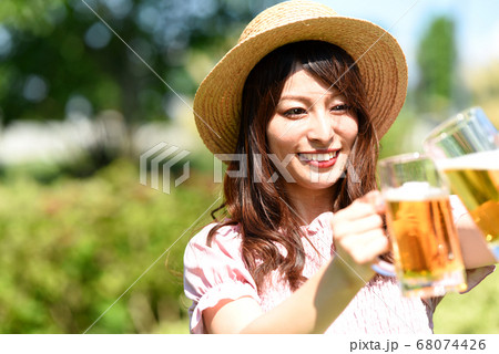 外でビールを持ちながら乾杯をする女性 68074426