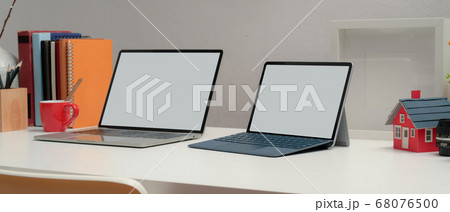 Two blank screen laptop on office desk with books Two blank screen laptop on office desk with books 68076500