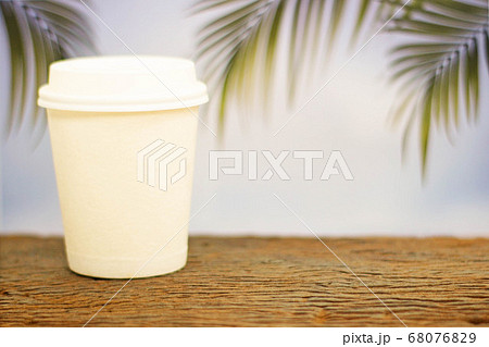 a coffee cup take home on wood on blurred palm 68076829