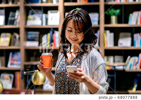 オフィスでスマホを操作する若いビジネスウーマン （カジュアル） 68077888