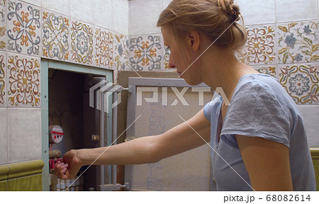 Woman shuts off water in an apartment Woman shuts off water in an apartment 68082614