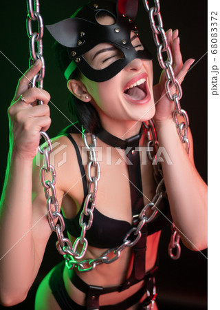 Hot brunette posing on a dark background in a belt and a cat mask with chains dancing a Striptease Hot brunette posing on a dark background in a belt and a cat mask with chains dancing a Striptease 68083372