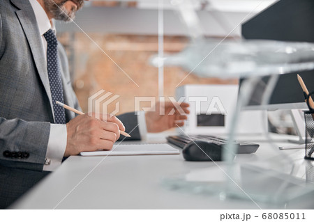 Male worker writing in spiral notebook in office 68085011