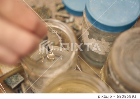 Jeweler holding a pendant with a pair of tweezers 68085993