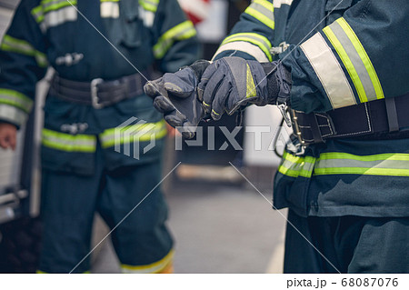 Portrait of strong hands of firefighter standing in front of another man Portrait of strong hands of firefighter standing in front of another man 68087076