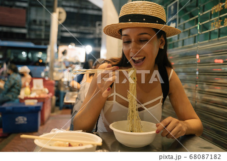 Young Hispanic Brunette woman eating noodles in street cafe 68087182
