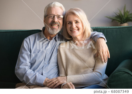 Happy senior couple bonding looking at camera sit on sofa 68087349