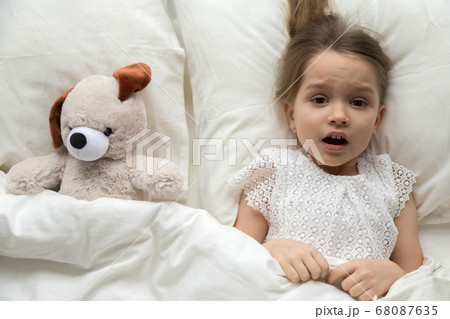 Scared child lying in bed with toy afraid of nightmare 68087635