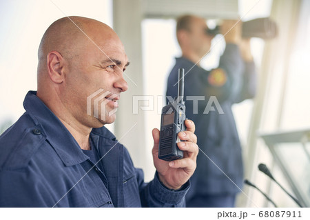 Smiling handsome worker holding walkie talkie in hand 68087911