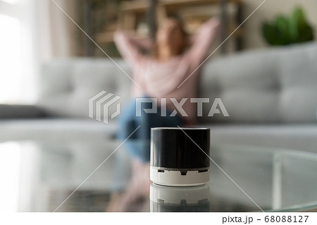 Portable wireless speaker on table with woman relaxing at home Portable wireless speaker on table with woman relaxing at home 68088127