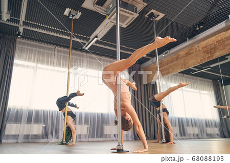 Beautiful female dancers performing pole dance tricks in studio 68088193