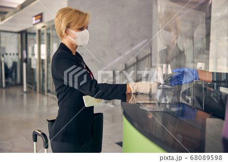 Charming businesswoman showing ticket at check-in desk in airport 68089598