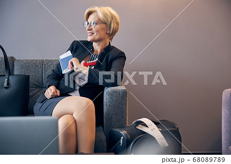 Beautiful woman sitting on couch in hall before business trip Beautiful woman sitting on couch in hall before business trip 68089789