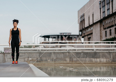 Beautiful athletic sportswoman on street. African american girl with closed eyes, in sportswear, with fitness tracker Beautiful athletic sportswoman on street. African american girl with closed eyes, in sportswear, with fitness tracker 68091279