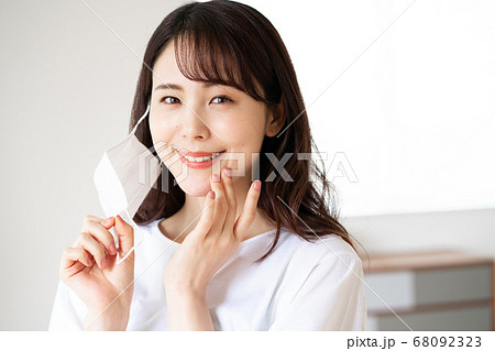 朝マスクをしようとする素顔の若い女性 68092323