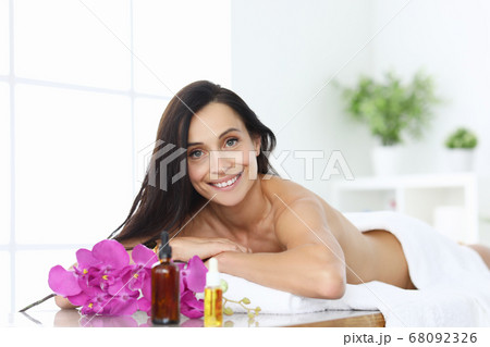 Woman in spa lies on massage table and smiles. Woman in spa lies on massage table and smiles. 68092326