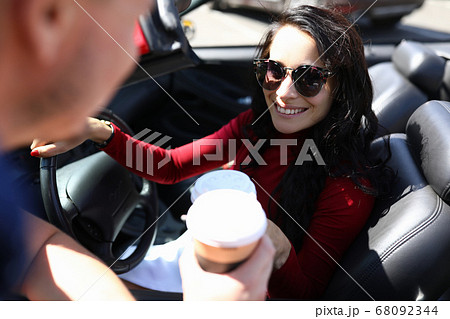 Woman sits in car smiling holds coffee in her hands next to man. Woman sits in car smiling holds coffee in her hands next to man. 68092344