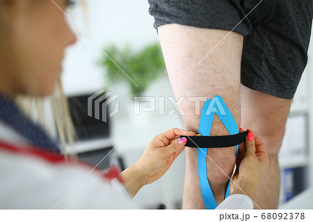 Fixation of kinesio tape on the patient's leg. Fixation of kinesio tape on the patient's leg. 68092378