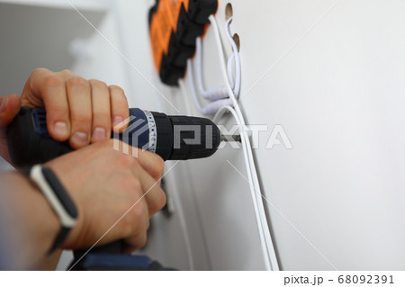 Man holds hammer drill in his hands and drills hole. 68092391
