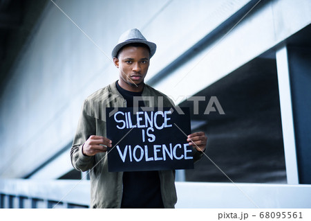 Man with silence is violence sign standing outdoors, black lives matter concept. Man with silence is violence sign standing outdoors, black lives matter concept. 68095561