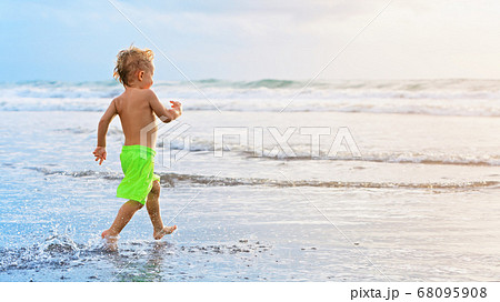 Child run with splashes by water pool along sea 68095908