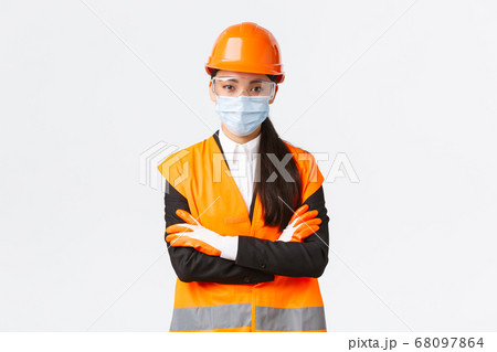 Covid-19 safety protocol at enterpise, construction and preventing virus concept. Confident asian female chief engineer looking how workers follow protocol during coronavirus, wear face mask Covid-19 safety protocol at enterpise, construction and preventing virus concept. Confident asian female chief engineer looking how workers follow protocol during coronavirus, wear face mask 68097864