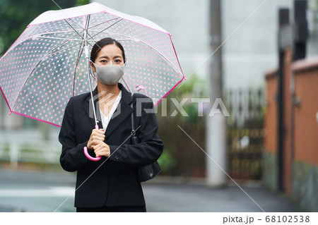 雨のが降る中マスクをしてビニール傘をさし通勤する女性 68102538
