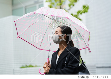 雨のが降る中マスクをしてビニール傘をさし通勤する女性 雨のが降る中マスクをしてビニール傘をさし通勤する女性 68102541