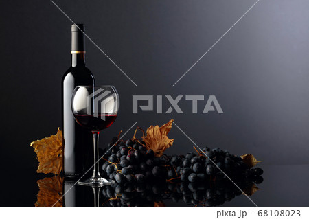 Red wine and grapes on a black reflective Red wine and grapes on a black reflective 68108023