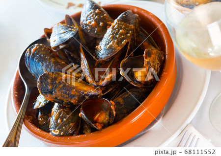 Delicious baked mussels on a bowl with spoon at table 68111552
