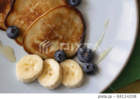 The pancakes on the plate are decorated with bananas, honey and blueberries, food and drink concept 68114208