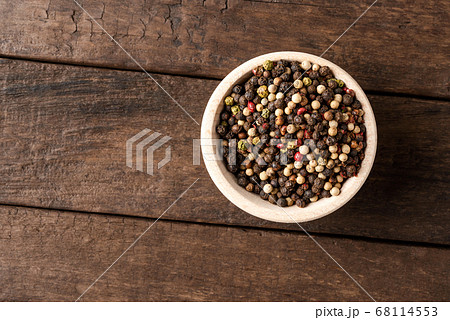 Mixed peppercorns in bowl on wooden table. Close up. Top view 68114553