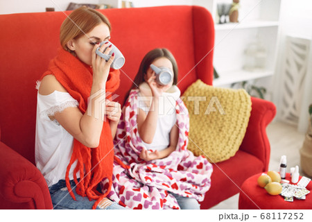 Mother gives her sick daughter hot tea 68117252