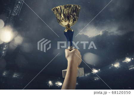 Award of victory, male hands tightening the cup of winners against cloudy dark sky Award of victory, male hands tightening the cup of winners against cloudy dark sky 68120350