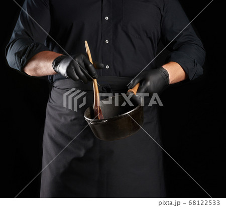 male cook in black uniform and latex gloves holds 68122533