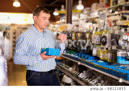Adult male is choose fasteners and screws in tools store 68122855