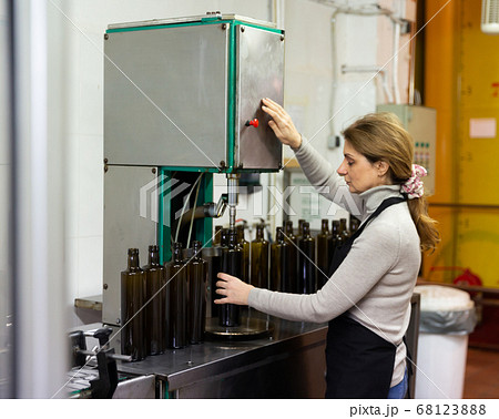 Woman working on olive oil bottling conveyor 68123888