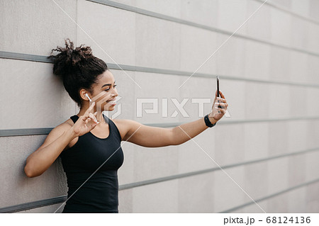 Sports blogger on street workout. Happy girl with fitness tracker makes selfie on smartphone Sports blogger on street workout. Happy girl with fitness tracker makes selfie on smartphone 68124136